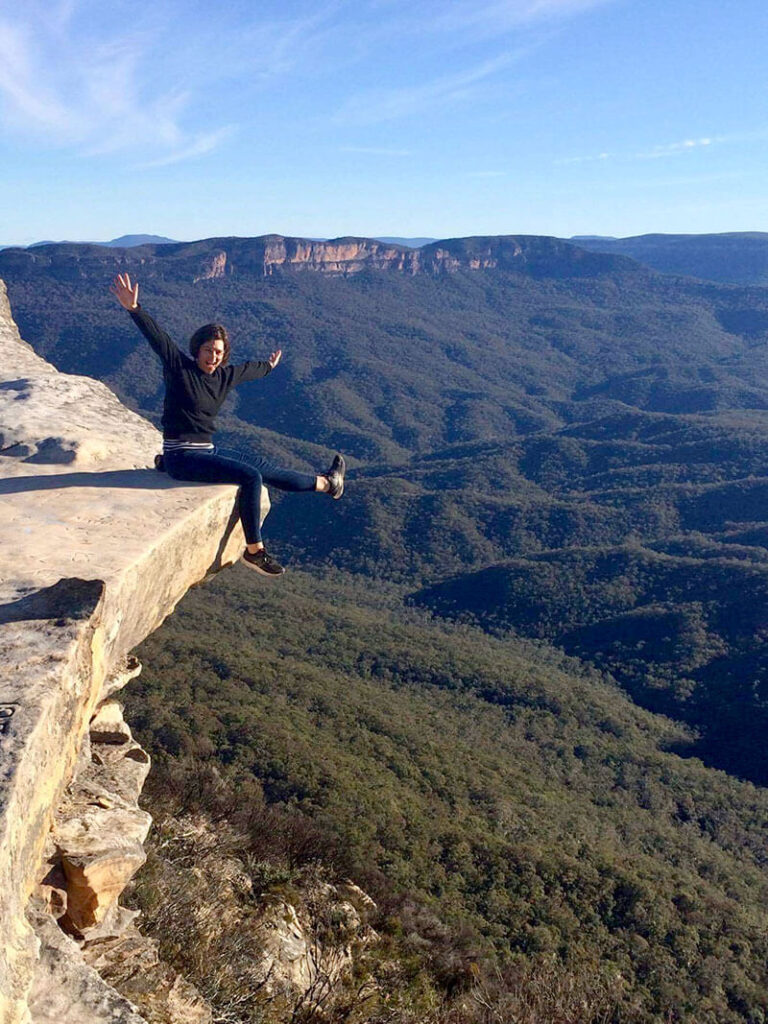 Lady sitting with her feet dangling over the edge of a cliff in the Blue Mountains Australia