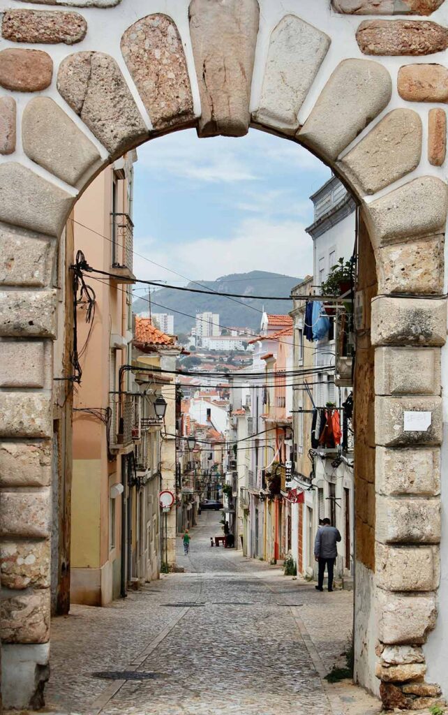 View through a stone archway down a narrow alley way in old town setubal