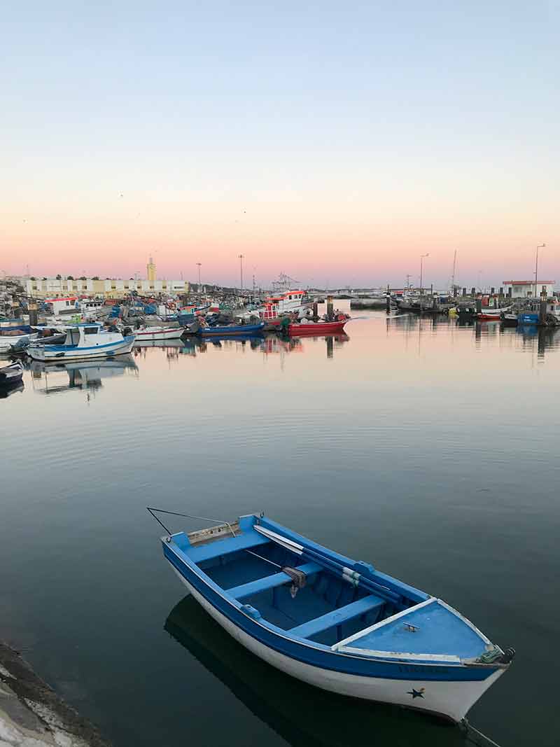 View of the setubal fishing port at sunset with an old row boat in the foreground