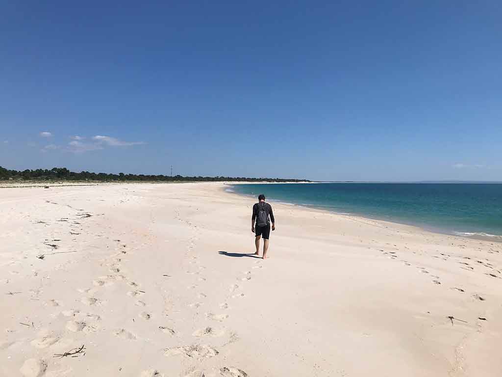 Man walks along a beach on the Trioa Peninsula